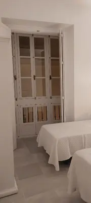 a white room with two beds and glass doors at el 2 de Flamenco 2ºA in Cádiz