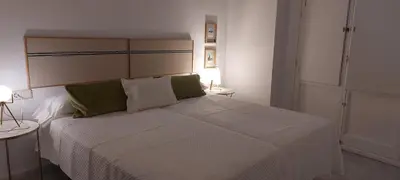 a bedroom with a large white bed with green pillows at el 2 de Flamenco 2ºA in Cádiz