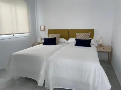 a bedroom with a large white bed with blue pillows at el 2 de Flamenco Ático 3ºB in Cádiz