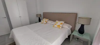 a bedroom with a white bed with pillows and a lamp at El 2 de Flamenco Ático 3ºA in Cádiz