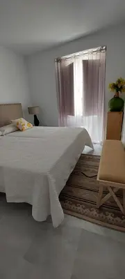 a bedroom with a bed with a window and a chair at El 2 de Flamenco Ático 3ºA in Cádiz