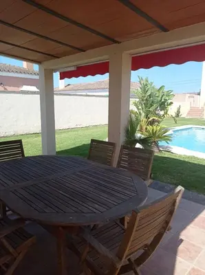 a table and chairs on a patio with a pool at El Vaivén in El Puerto de Santa María