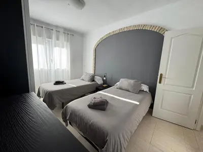 a bedroom with two beds and a window at Aires de Regla, Apartamentos Living Sur in Chipiona