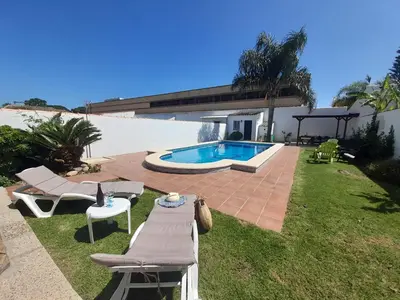 a backyard with a pool and a table and chairs at Villa Lolera in Chiclana de la Frontera