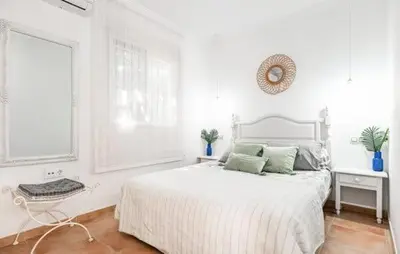 a white bedroom with a white bed and a window at Villa Lolera in Chiclana de la Frontera
