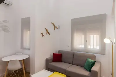 a living room with a couch and birds on the wall at El Duplex de Barrocal in Cádiz