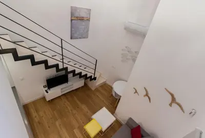 a white room with a staircase with a tv and a table at El Duplex de Barrocal in Cádiz