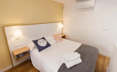 a small bedroom with a white bed with towels on it at El Duplex de Barrocal in Cádiz