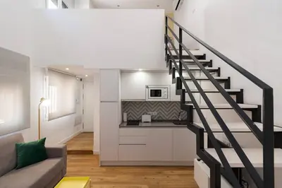 a living room with a staircase leading to a kitchen at El Duplex de Barrocal in Cádiz