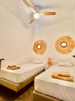 two beds in a room with a ceiling fan and mirrors at La Primera de Occidente in Cádiz