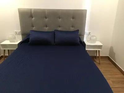 a bed with a blue comforter and two tables at Las Casitas in Conil de la Frontera
