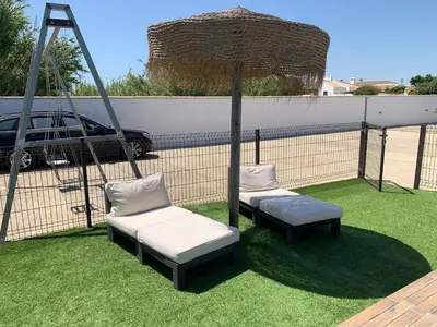 two chairs and an umbrella on the grass at Las Casitas in Conil de la Frontera