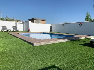 a backyard with a swimming pool and green grass at Las Casitas in Conil de la Frontera