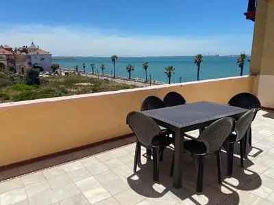 a table and chairs on a balcony with a view of the ocean at Apartamento terraza puerto sherry. in El Puerto de Santa María