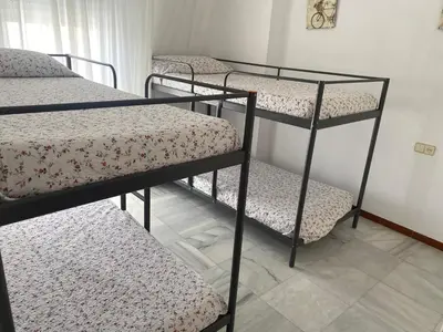 a room with three bunk beds in a room at Apartamento terraza puerto sherry. in El Puerto de Santa María