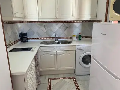 a kitchen with a sink and a washing machine at Apartamento terraza puerto sherry. in El Puerto de Santa María
