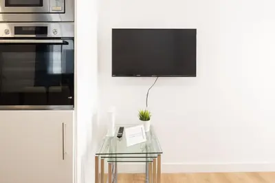 a kitchen with a glass table with a tv on a wall at El Sol & la Sal de Cádiz Little Apartments in Cádiz