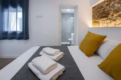 a bedroom with a white bed with yellow pillows and towels at El Sol & la Sal de Cádiz Little Apartments in Cádiz