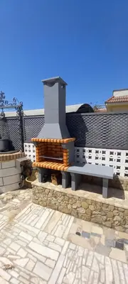 a stone patio with a bench and a fireplace at Villa Antonia in Chipiona