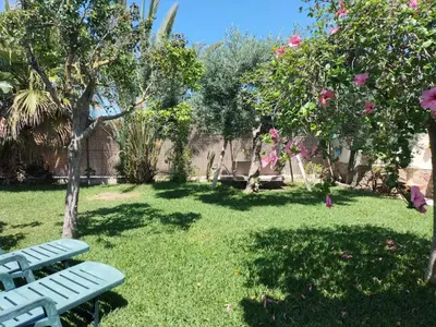 a park bench in a yard with a tree and flowers at Villa Antonia in Chipiona