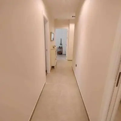 a long hallway with a white wall and a white floor at Estupendo Piso Nuevo en Playa Victoria in Cádiz