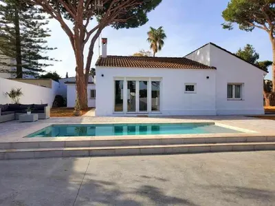 a house with a swimming pool in front of a house at Villa Yoli 26 con Piscina y Jardin cerca de la Playa in Chiclana de la Frontera