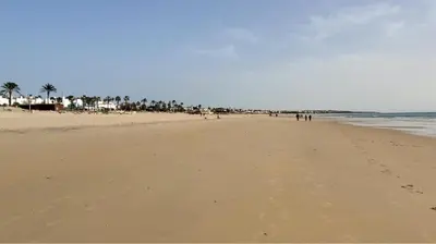 a group of people walking on the beach at Villa Yoli 26 con Piscina y Jardin cerca de la Playa in Chiclana de la Frontera