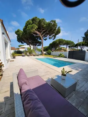a swimming pool with a purple couch in front of a house at Villa Yoli 26 con Piscina y Jardin cerca de la Playa in Chiclana de la Frontera