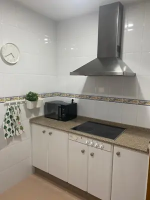 a kitchen with white cabinets and a stove top oven at Apartamento Tía Maria in Cádiz