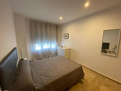 a small bedroom with a bed and a mirror at Apartamento Tía Maria in Cádiz