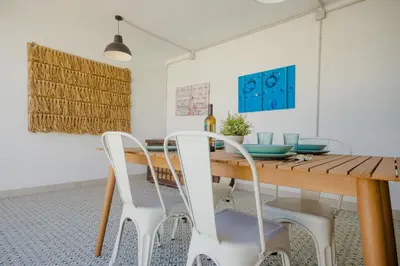 a dining room with a wooden table and white chairs at Villa Minerva in Chiclana de la Frontera