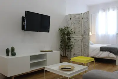 a white living room with a tv on a wall at Encanto de la Catedral Ha Loft in Cádiz