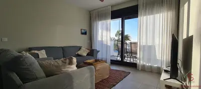 a living room with a gray couch and a television at Arenas de Doñana by Sanlúcar Housing in Sanlúcar de Barrameda