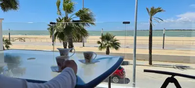 a person sitting at a table with a view of the beach at Arenas de Doñana by Sanlúcar Housing in Sanlúcar de Barrameda