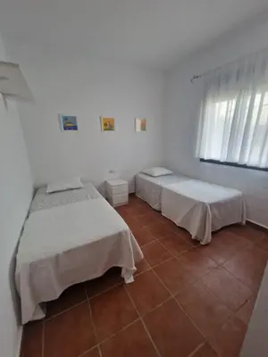 two beds in a room with white walls and a tile floor at Casa Alma in Conil de la Frontera