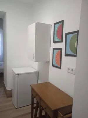 a small kitchen with a table and a refrigerator at La Fuente Apartamento Jerez in Jerez de la Frontera