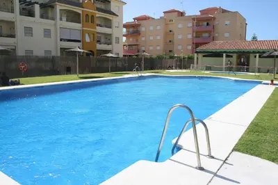a large blue swimming pool with buildings in the background at Apartamento Costa de la Luz - Parking y Terraza in Chipiona