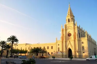 a large yellow building with a clock tower on it at Apartamento Costa de la Luz - Parking y Terraza in Chipiona