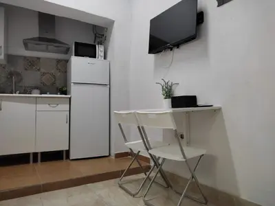 a kitchen with a white refrigerator and a table and chairs at El Tabanquito in Jerez de la Frontera