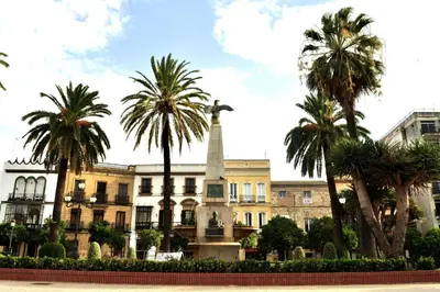a monument in front of a building with palm trees at El Tabanquito in Jerez de la Frontera