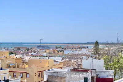 a city with buildings and the ocean in the background at Apartamento Montefillo in Sanlúcar de Barrameda