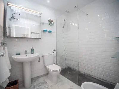 a white bathroom with a toilet and a sink at Apartamento Montefillo in Sanlúcar de Barrameda