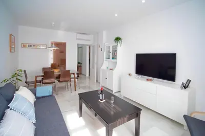 a living room with a couch and a tv and a table at Apartamento Montefillo in Sanlúcar de Barrameda