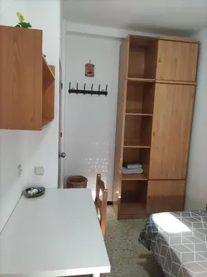 a room with a table and a book shelf at Comparte Espacio en Chiclana in Chiclana de la Frontera