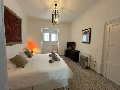 a bedroom with a large white bed and a television at HABITACION POLEO in Sanlúcar de Barrameda