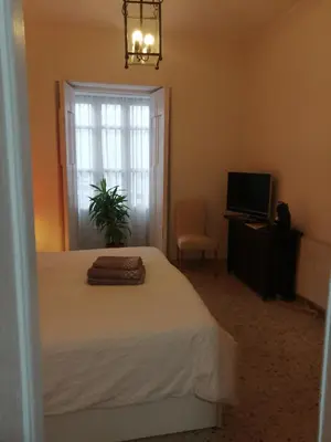 a bedroom with a bed and a television and a window at HABITACION POLEO in Sanlúcar de Barrameda