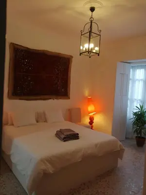 a bedroom with a bed and a chandelier at HABITACION POLEO in Sanlúcar de Barrameda