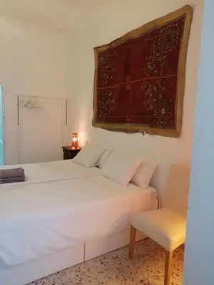 a bedroom with a white bed and a chair at HABITACION POLEO in Sanlúcar de Barrameda