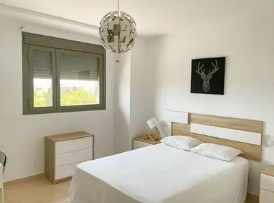 a white bedroom with a bed and a window at Apartamento moderno con vistas in El Puerto de Santa María