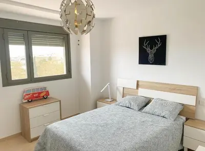 a bedroom with a bed and a window and a chandelier at Apartamento moderno con vistas in El Puerto de Santa María